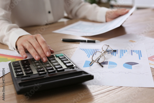 Tax accountant with calculator working at wooden table  closeup
