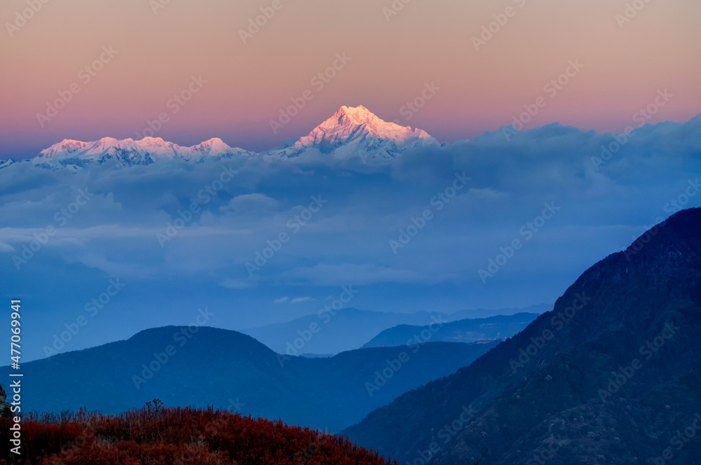 Beautiful first light from sunrise on Mount Kanchenjugha, Himalayan mountain range, Sikkim, India. Blue coloured clouds surrounded the mountains at dawn