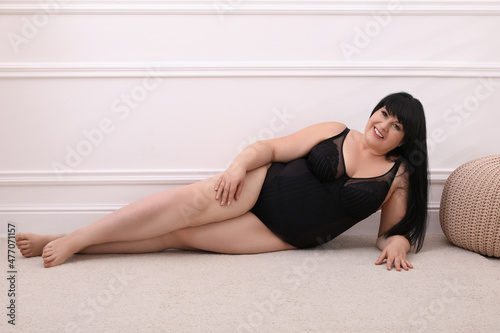 Beautiful overweight woman in black underwear posing at home. Plus-size model