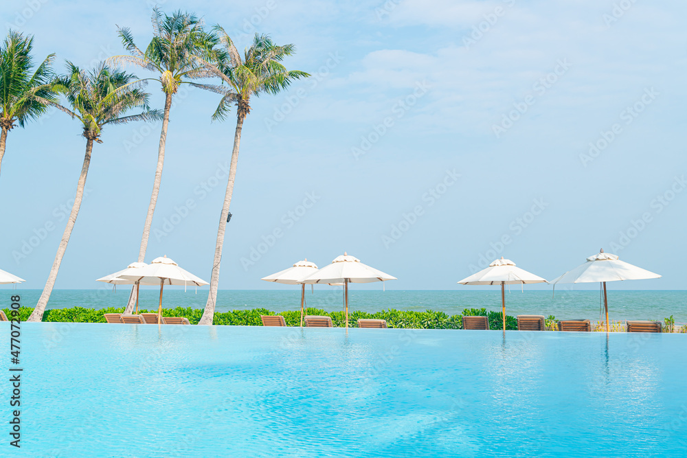 Naklejka premium umbrella with bed pool around swimming pool with ocean sea background