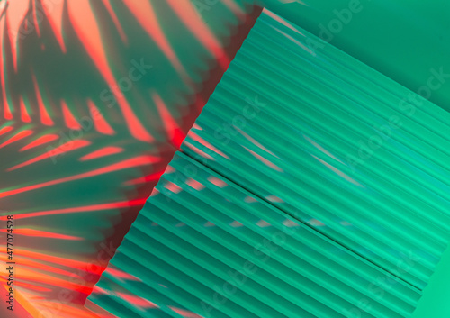 Fototapeta Naklejka Na Ścianę i Meble -  Palm tree leaves on abstract background with podiums in neon light. Trendy geometric shapes for products. Red and green gradient light. Minimalism, 90s, 80s concept.