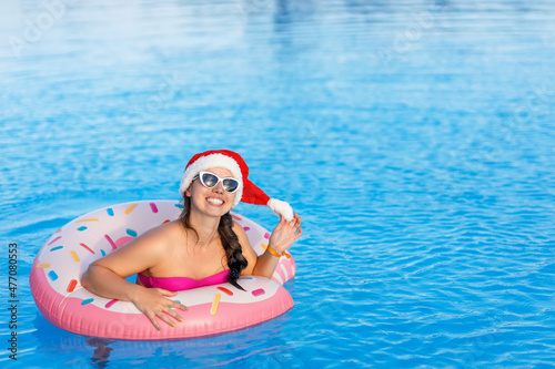 attractive young woman in santa hat and sunglasses relaxing on inflatable ring in swimming pool © alter_photo