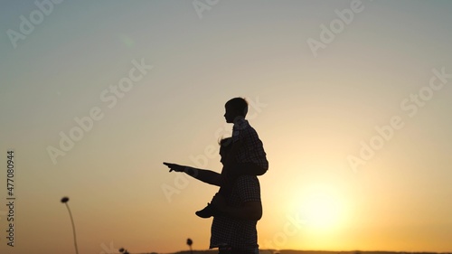 The son is sitting on the shoulders of his father, playing in the park in summer. Father, little child, play, fantasize with the child at sunset in the spring. Kid, daddy walk. Happy family outdoors