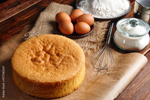 Fényképezés Homemade round sponge cake or chiffon cake on baking paper so soft and delicious with ingredients: eggs, flour, milk on wood table