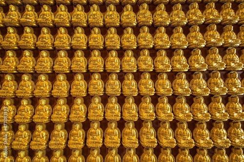 Bangkok, Thailand - December, 20, 2021 : Many golden buddha statues arrange by row and column at the wall in Wat Leng Nei Yee 2 Temple at Bangkok, Thailand. photo