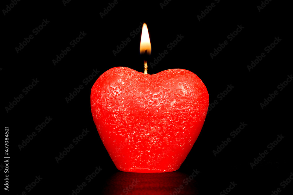 Candle in the shape of a heart. A close-up of a burning candle. Candle in the shape of a heart. A close-up of a burning candle.