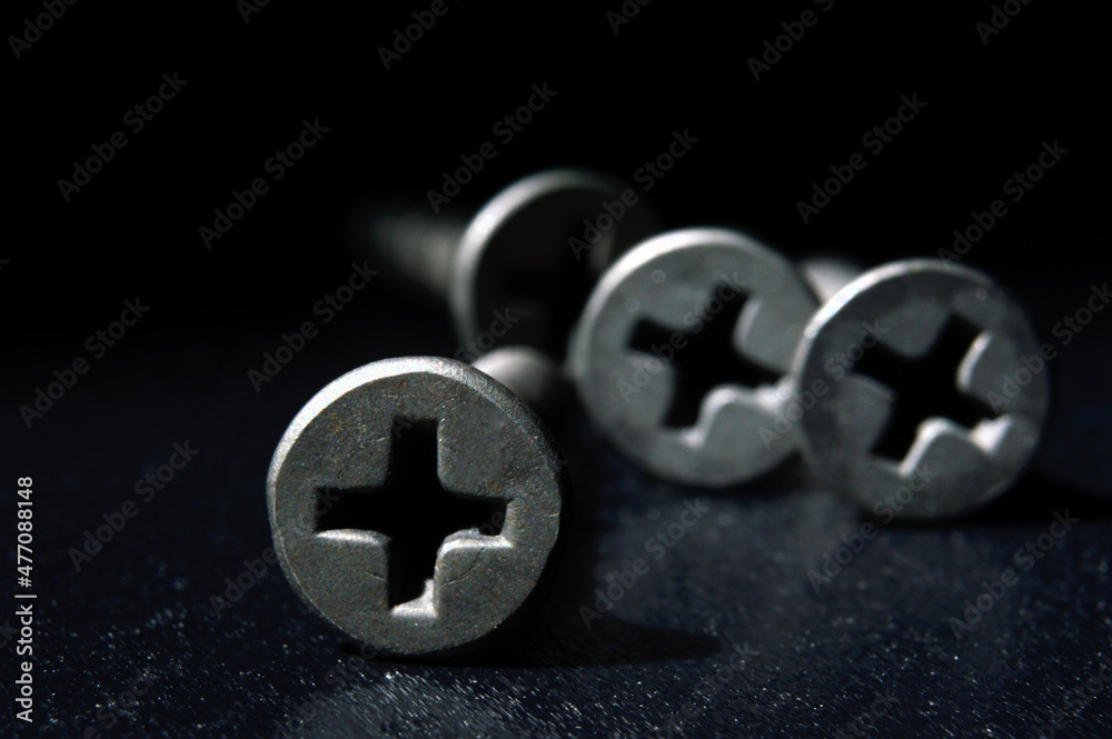 black hardened self-tapping screws lies on a dark background. close-up. black hardened self-tapping screws lies on a dark background. close-up.