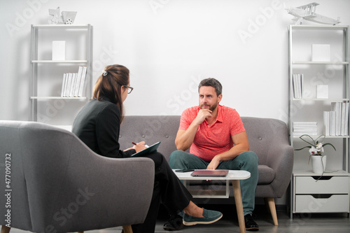 Middle aged man problem therapy. Handsome man is sitting on couch and talking to the psychologist. Psychology patient is telling about her mental health during psychological consultation.