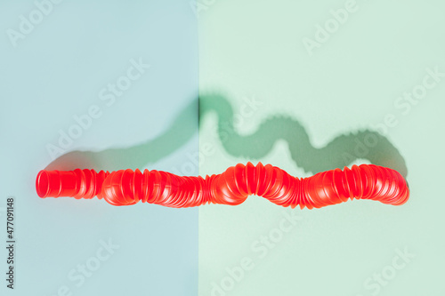 The curved pop tube stands leaning against the wall. Modern still life with antistress toy