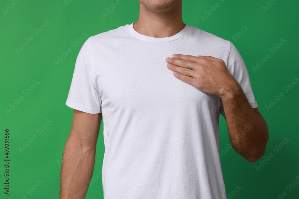 Man holding hand near chest on green background, closeup Man holding hand near chest on green background, closeup
