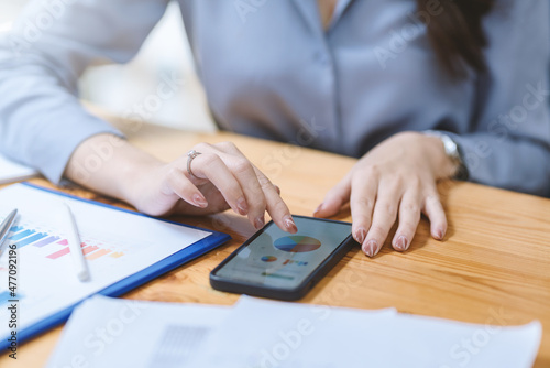 Woman trading stock on mobile phone. Businesswoman looking at financial information on smartphone. Close up.