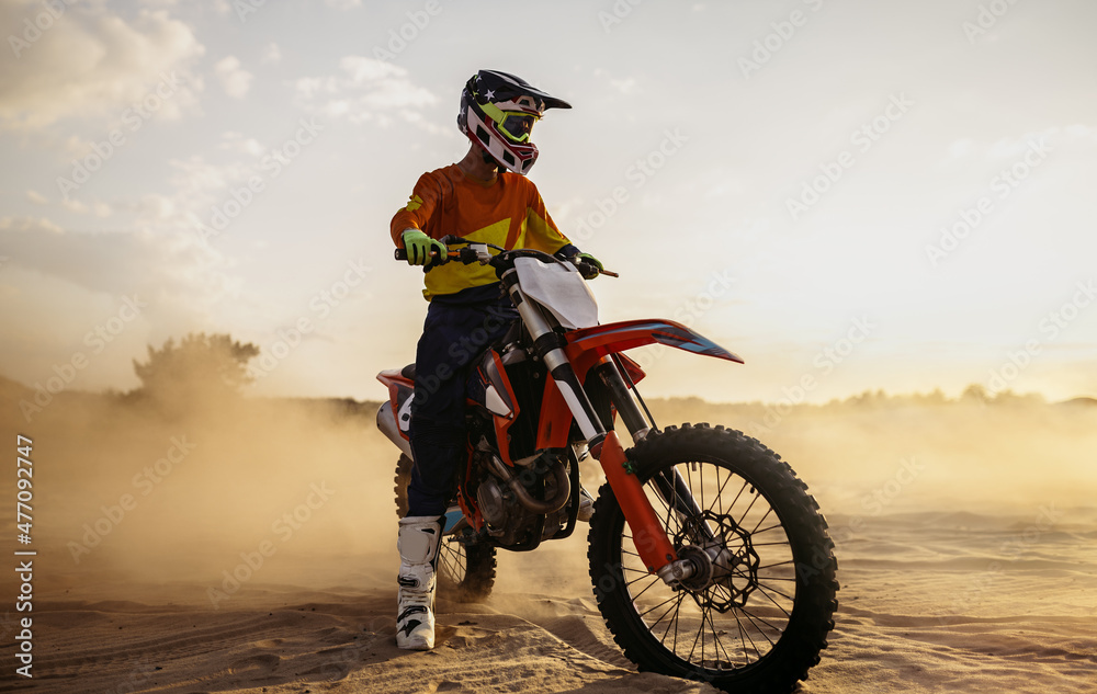 Naklejka premium Motocross rider on sportmotor over dust landscape
