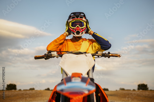 Fototapeta Portrait of motocross rider taking off helmet