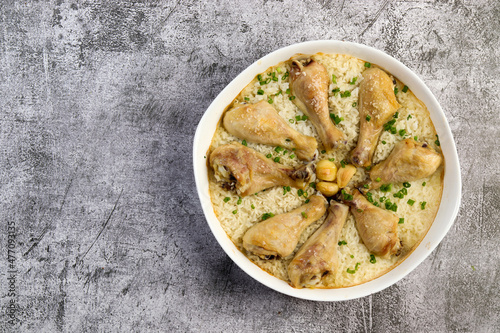 One-Pan Chicken Drumsticks with Rice in a white baking dish on a dark grey background. Top view, flat lay