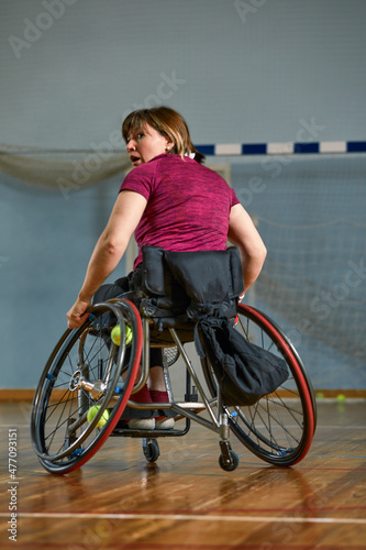 Disabled young woman on wheelchair playing tennis on tennis court