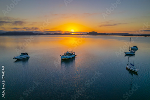 Sunrise waterscape with boats, soft clouds and reflections