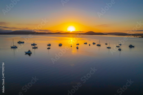 Sunrise waterscape with boats, soft clouds and reflections