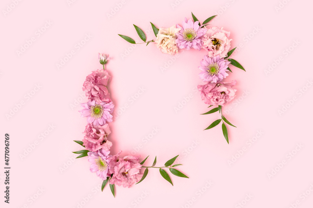 Flower border frame made of eustoma on a pink pastel background. Greeting card template with copyspace.