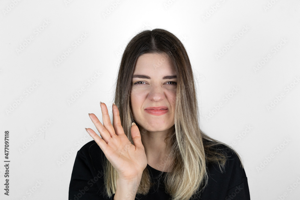 Displeased woman covers nose with hand, smells something awful, pinches nose, frowns in displeasure, sees pile of garbage, dressed in casual clothes, isolated on white background. Bad odour.