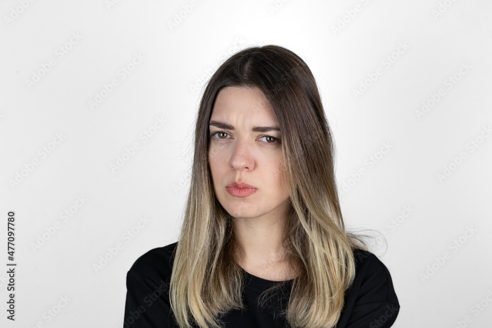 Young girl with serious and angry expression on her face. She is in anger. She asked something and she is waiting answer. White studio background. Young girl with serious and angry expression on her face. She is in anger. She asked something and she is waiting answer. White studio background.
