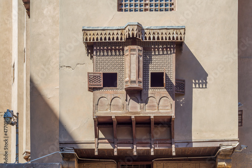 Mamluk era style oriel window covered by interleaved wooden grid - Mashrabiya, on shabby grunge external wall, at historical House of Egyptian Architecture, old Cairo, Egypt photo