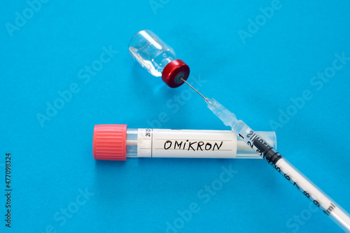 Medical syringe in vial with Omicron swab tube against blue background photo