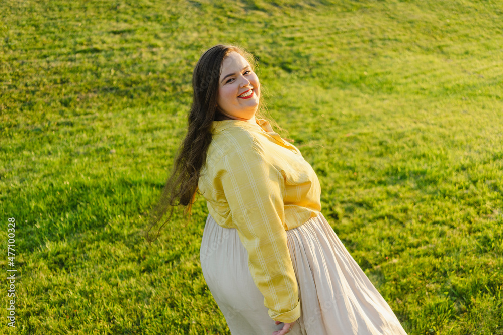Smiling plus size woman looking over shoulder at sunset Smiling plus size woman looking over shoulder at sunset