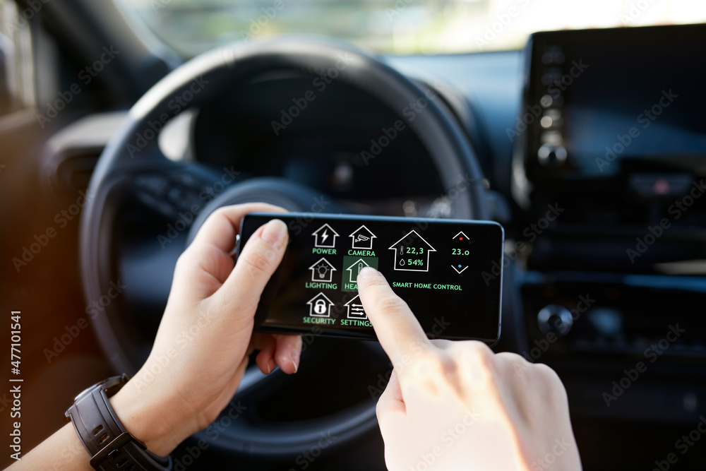 Businesswoman controlling smart house through mobile phone while sitting in car Businesswoman controlling smart house through mobile phone while sitting in car