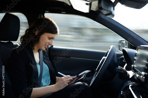 Smiling businesswoman using tablet PC in autonomous driving car photo