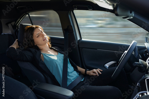 Tired businesswoman sleeping in autonomous driverless car photo