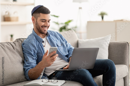 Happy jewish man using mobile phone and laptop