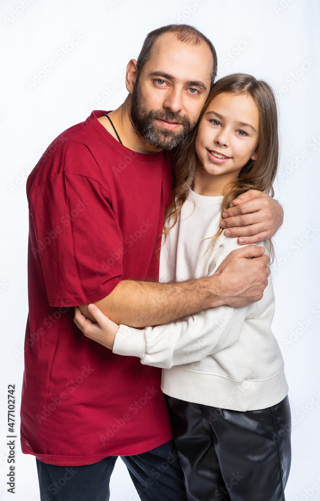 dad hugs daughter by the shoulders in the studio. a man in a burgundy-red T-shirt, a girl in a white sweatshirt. isolated white background dad hugs daughter by the shoulders in the studio. a man in a burgundy-red T-shirt, a girl in a white sweatshirt. isolated white background