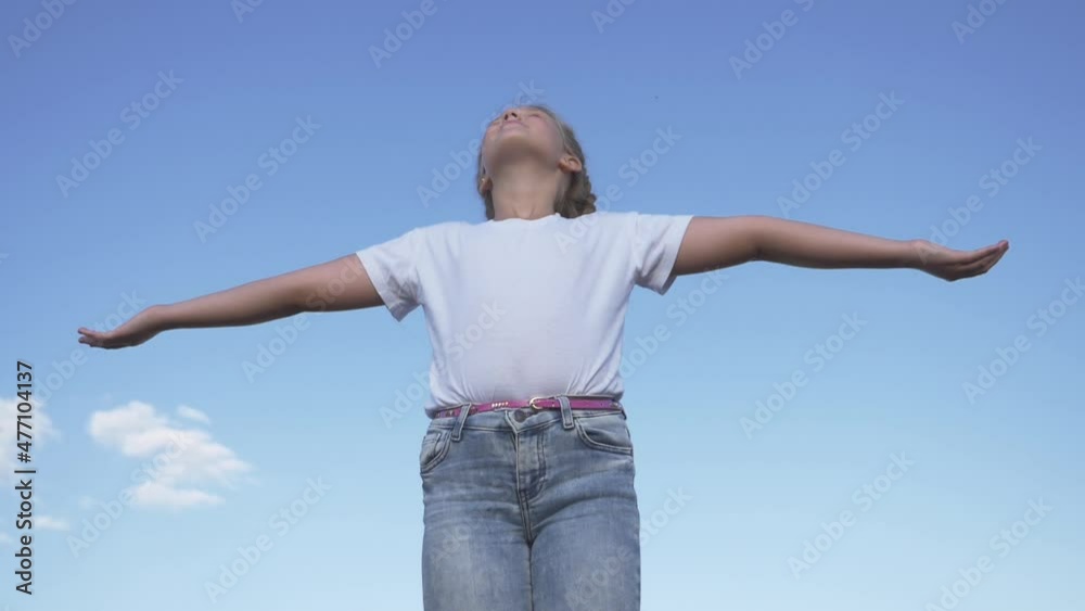 Happy child on background sky.girl stands with raised arms in sunny blue sky outdoors.child enjoys freedom, happiness, raising his hands up.girl of freedom, happiness, enjoying nature while traveling. Happy child on background sky.girl stands with raised arms in sunny blue sky outdoors.child enjoys freedom, happiness, raising his hands up.girl of freedom, happiness, enjoying nature while traveling.