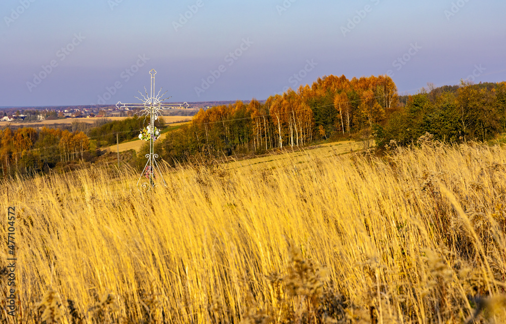 Autumn panoramic view of hills with fields and meadows with field cross shrine surrounding Zagorzyce village south Sedziszow Malopolski town in Podkarpacie region of Lesser Poland - obrazy, fototapety, plakaty 