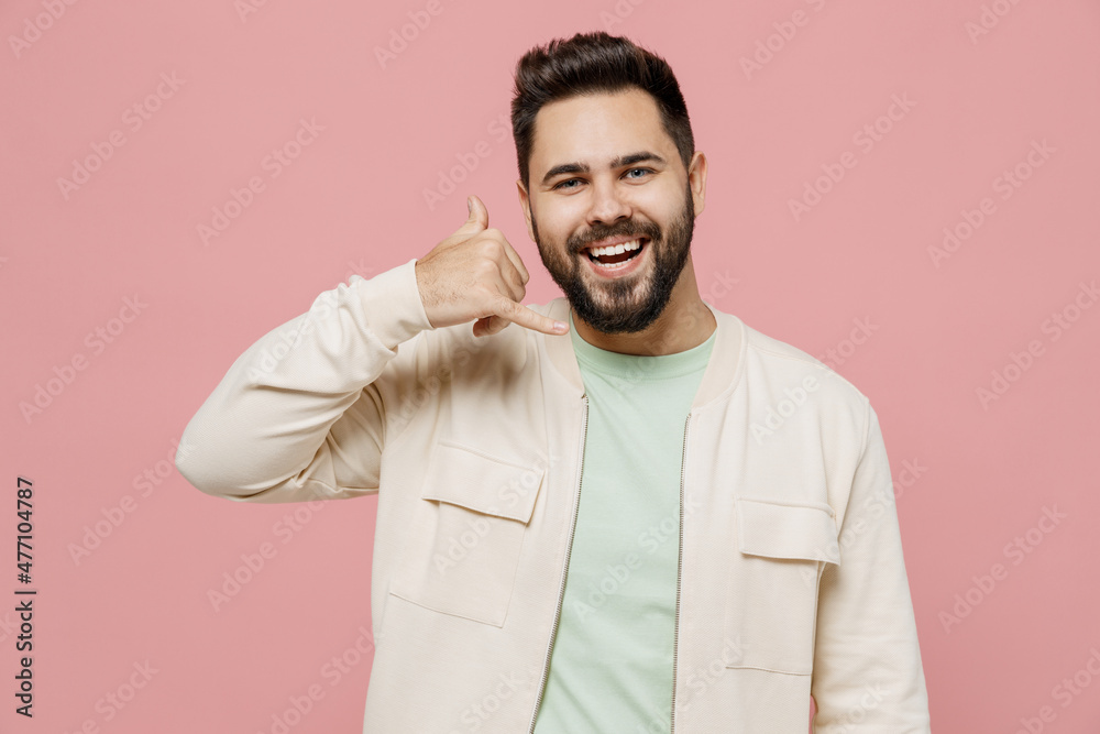 Young smiling fun happy caucasian man 20s wear trendy jacket shirt doing phone gesture like says call me back isolated on plain pastel light pink background studio portrait. People lifestyle concept. Young smiling fun happy caucasian man 20s wear trendy jacket shirt doing phone gesture like says call me back isolated on plain pastel light pink background studio portrait. People lifestyle concept.
