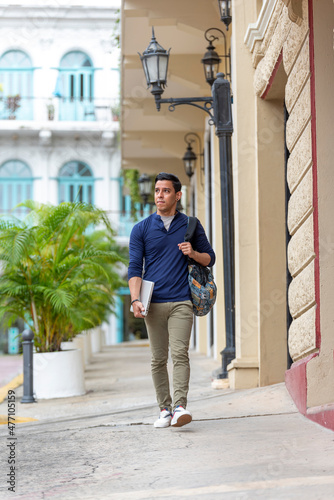 young latino man walking down the street with his laptop, Panama city, Central America