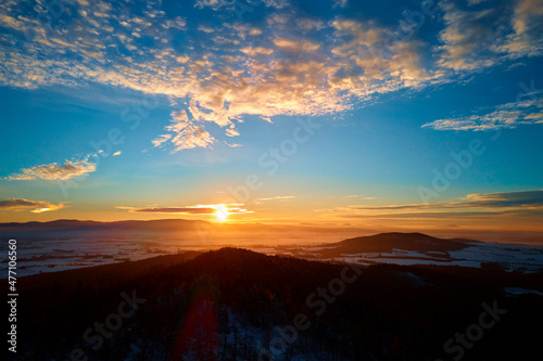 Sunset over mountans covered with forest, beautiful winter landscape, nature background, aerial view
