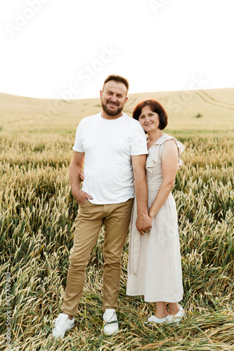 portrait of a middle-aged couple in nature. husband and wife are smiling cute while in the field on the back of the day.. happy man with woman of retirement age
