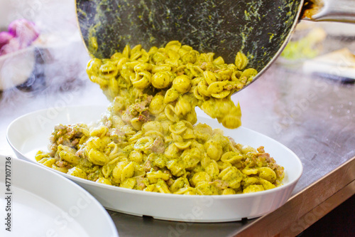 Pirofila di orecchiette pugliesi fumanti con broccoli, salsicce e formaggio photo