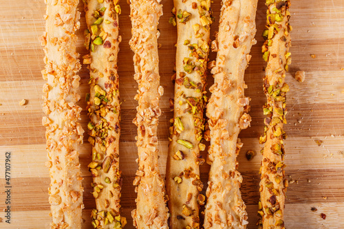 Grissini di pane ricoperti con granella di pistacchio e mandorle fotografati su un tagliere di legno photo