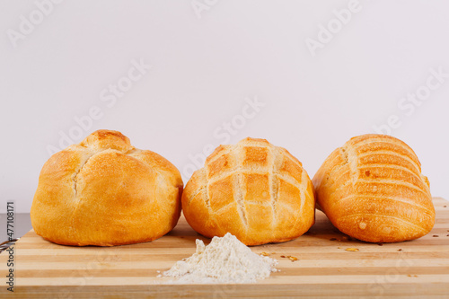 Tre panini appena sfornati e di diverse dimensioni fotografati con una piccola montagnetta di farina davanti