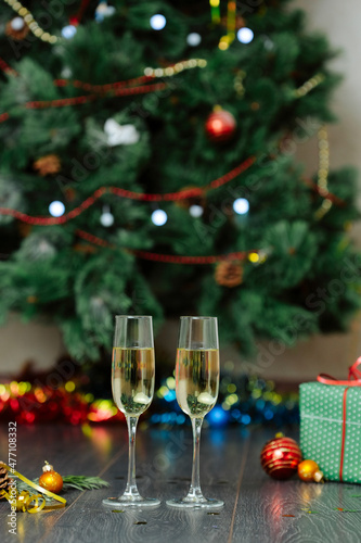 Champagne glasses and gifts  with New Year s toys near the Christmas tree decorated with colorful lights and a garland.Happy New year celebration concept. 