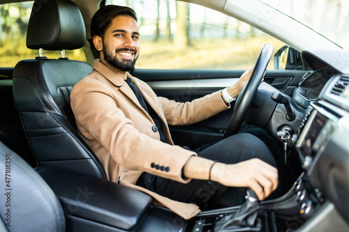 Success in motion. Handsome indian young man in full suit smiling while driving a car © F8  \ Suport Ukraine