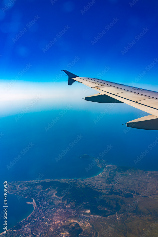 View from the airplane window at a beautiful blue clear sky and the airplane wing View from the airplane window at a beautiful blue clear sky and the airplane wing