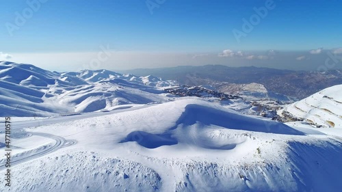Aerial winter view with mountains covered by snow. Sunny day. Mountain peak with snow. Ski slopes