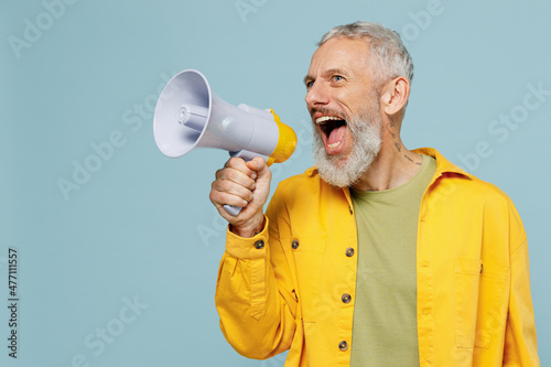 Elderly gray-haired mustache bearded man 50s in yellow shirt hold scream in megaphone announces discounts sale Hurry up isolated on plain pastel light blue background studio People lifestyle concept