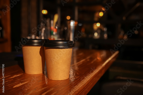 Paper coffee cups on wooden table in cafe. Space for text