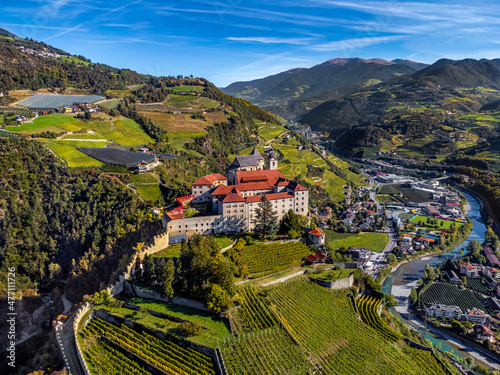 Klausen, Italy - Aerial view of the Säben Abbey (Monastero di Sabiona) with Chiusa (Klausen) comune northeast of the city of Bolzano and South Tyrol Dolomites at background on a sunny summer day