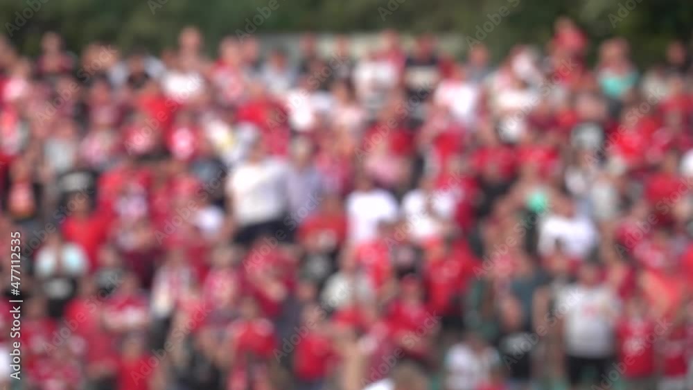 Many fans supporting soccer team at stadium. Blurred crowd of people at football stadium. Slow motion