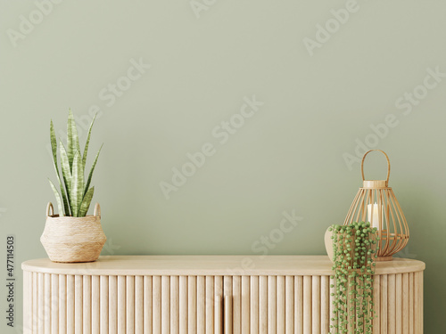 Interior mockup with empty green wall, wooden slat curved sideboars, wicker lantern and trendy plants. 3D rendering, illustration